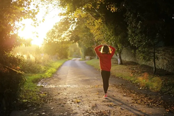 person wearing running gear, walking away on path outside, viewed from behind